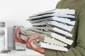 person holding stack of keyboards