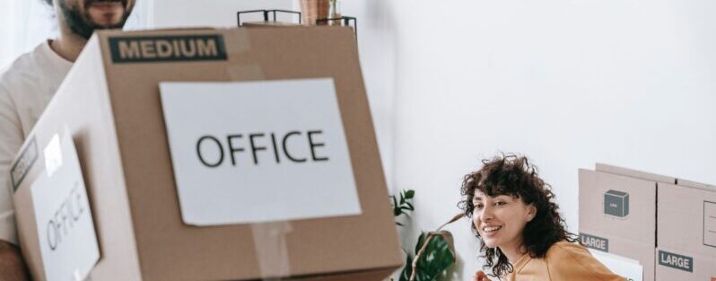 man moving box while woman watches